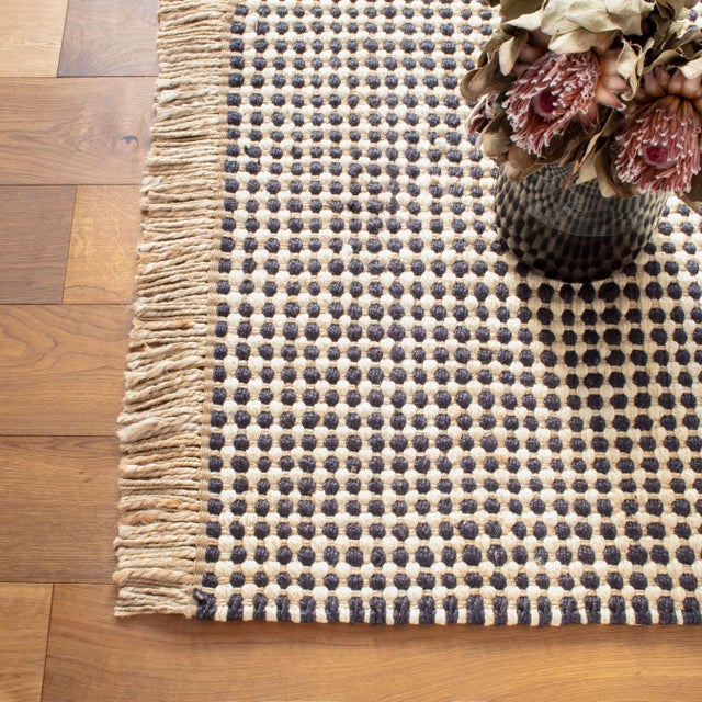 Multi-stranded flatweave rug has a natural warp and alternating black and ivory chunky weft for a textural check that...