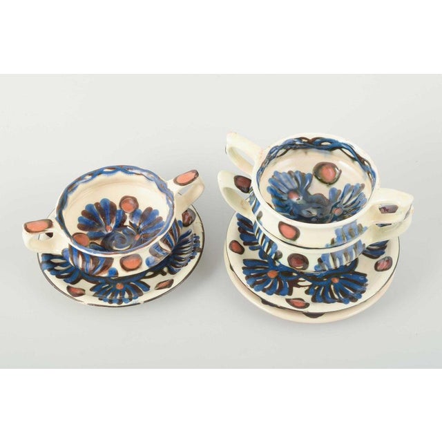 Three bouillon cups with matching saucers, glazed ceramics hand-decorated with polychrome floral motifs in blue, brown,...