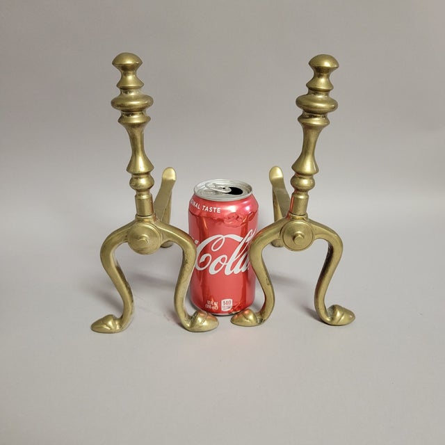 A charming pair of vintage solid brass miniature andirons — originally designed as small mantel or hearth-edge rests used...