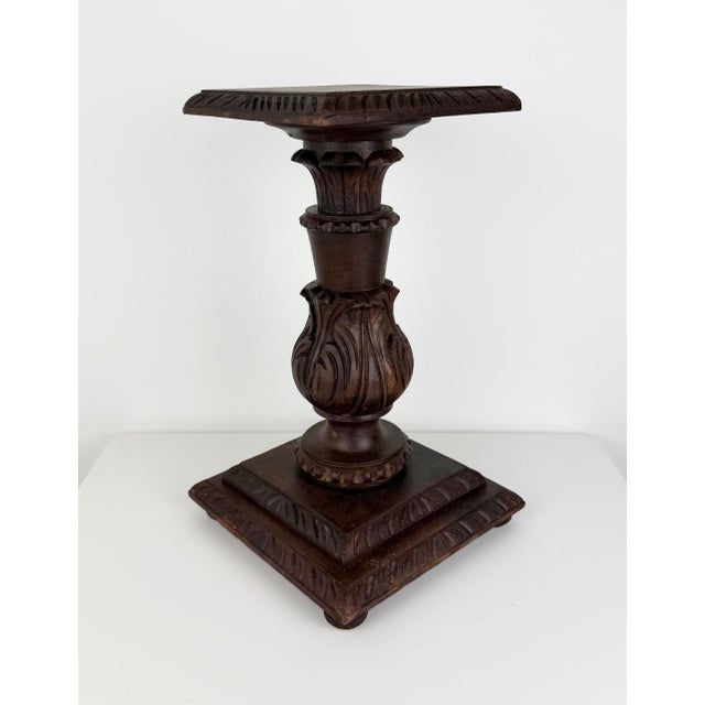 Antique carved wooden pedestal stand featuring an ornate floral and foliate design, a rich dark wood finish, and a square...