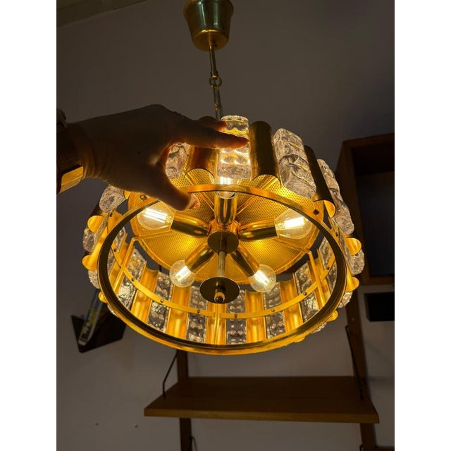 Luxurious Swedish glass art: This pendant lamp, crafted from gleaming brass and solid glass, was designed by renowned...