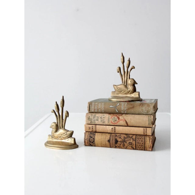 These vintage brass bookends feature a classic duckling with cattails design, perfect for adding character and style to...
