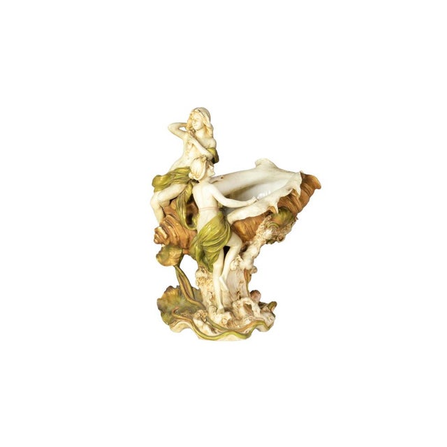 An Art Nouveau porcelain centerpiece from the early 20th century, featuring two nymph-like maidens emerging from a large...