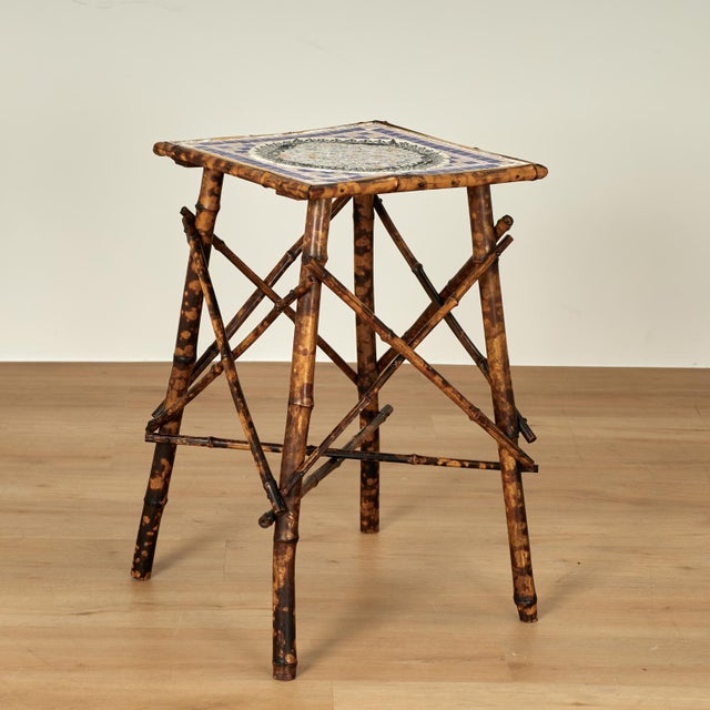 Standout 19th century English stand crafted in burnt bamboo with an square top and triangular base, having later tile work...
