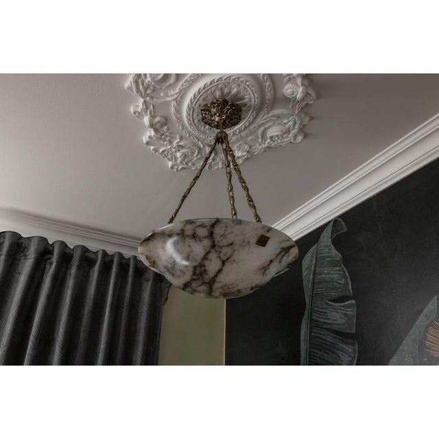 Elegant french art deco pendant light featuring richly veined alabaster and refined metal detailing. this elegant french...