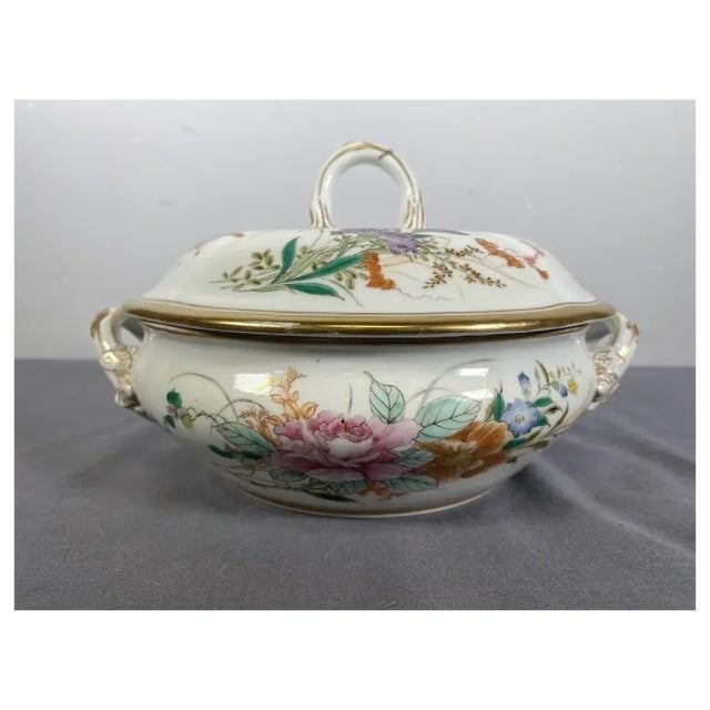 An Antique Chinese Export Tureen. The Tureen is made of porcelain and features delicate hand painted flowers and insects;...