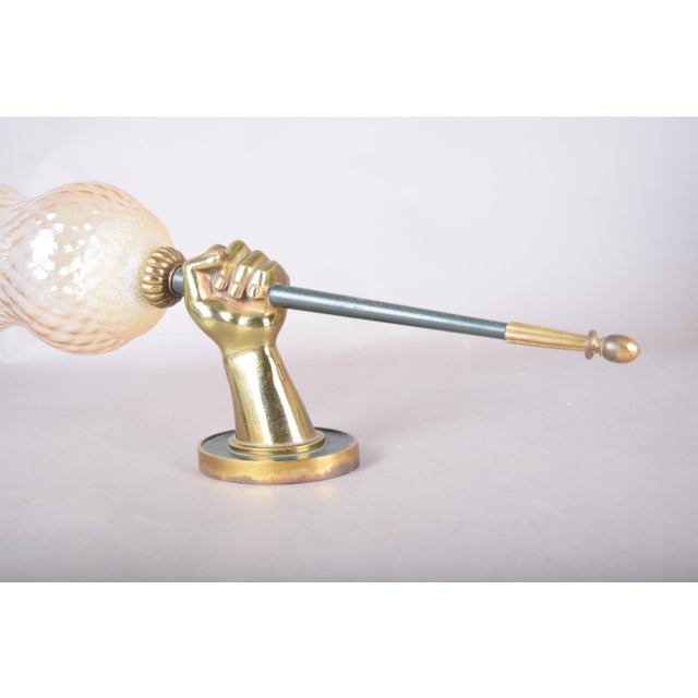 Sculptural wall sconce in the style of Maison Jansen, with a bronze fist gripping a slender torch-like rod. The rod has a...