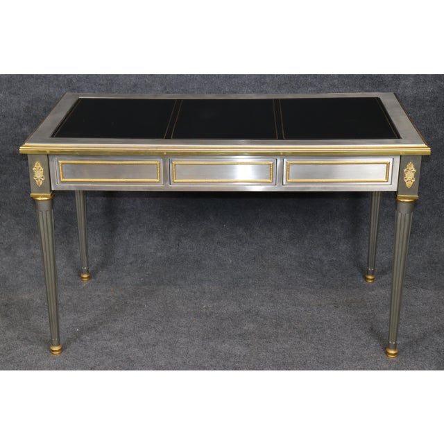 This sophisticated steel, bronze, and leather writing desk, in the style of John Vesey, is an elegant interpretation of...