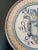 A beautiful hand painted blue, cream, and yellow faience pottery wall plate featuring a coat of arms crest. By Fidia...