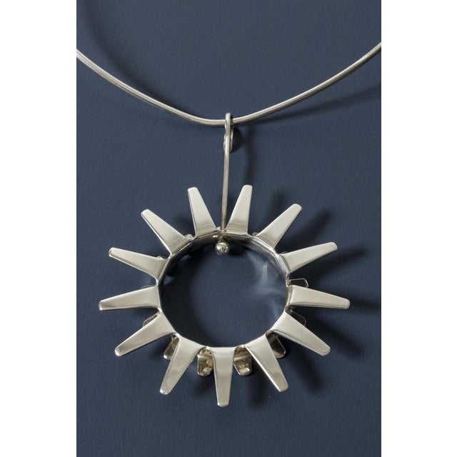 Amazing silver neck ring by Tone Vigeland, with a large stylized pendant in the form of a sun. Vivacious and graphic, a...