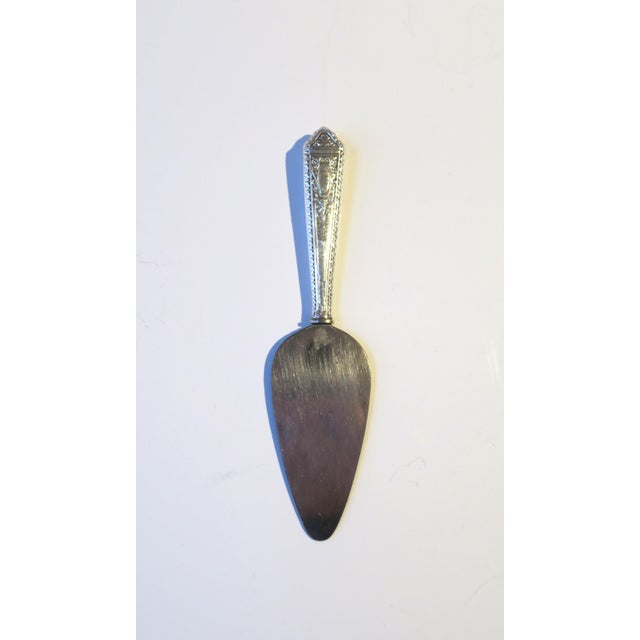 A sterling silver appetizer spreader, circa early-20th century. Pieces' sterling silver handle has a repousse design of...