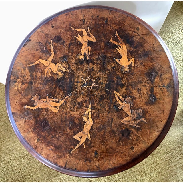 This whimsical Continental side table has been decorated on top with marquetry of six dandies each suspended by a cable...