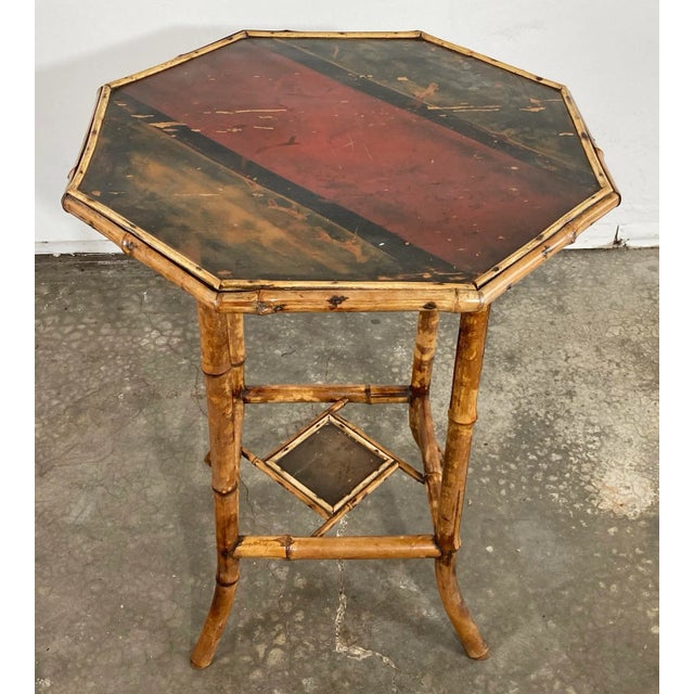 Antique Chinoiserie style bamboo side table featuring beautifully hand-painted design to tabletop and lower accent riser....