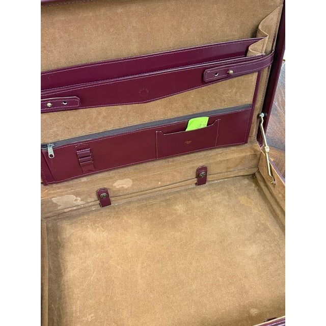 Elegant burgundy leather attaché case featuring an embossed Cartier double-C emblem and a gold-coloured “Cartier Paris”...