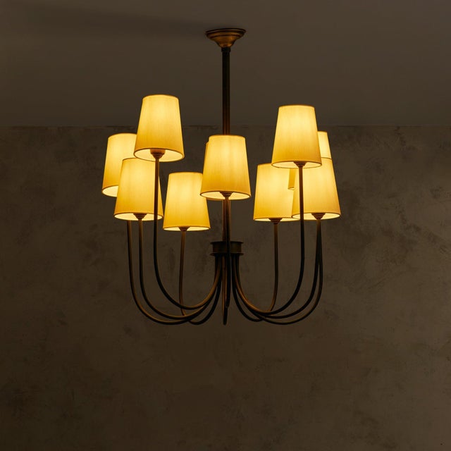 A mid-20th century French chandelier, wrought in blackened iron with ten sweeping arms that curve outward in perfect...
