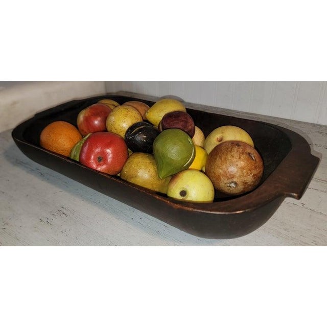 This 19thc wood dough bowl with a collection of 24 pcs. of stone fruit or alabaster fruit.This collection includes the...