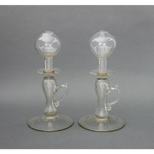 Group of Four Murano Art Glass Articles, comprising: a pair of colorless glass oil lamps, a clear glass footed vase, and...