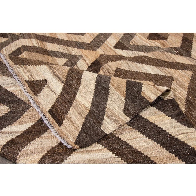 21st century modern Turkish Kilim rug with an all-over geometric, interlocking diamond pattern in dark brown and beige....