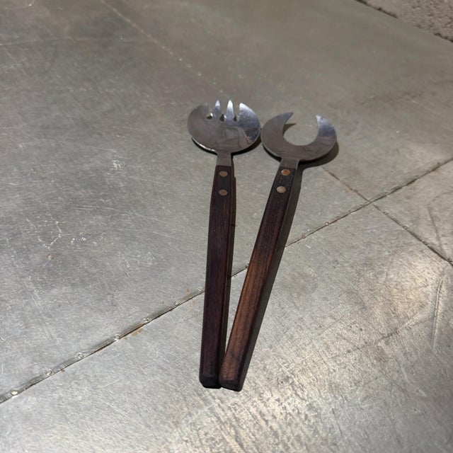 For your consideration, a vintage Mid-Century Modern (MCM) salad server set featuring stainless steel heads and long wood...
