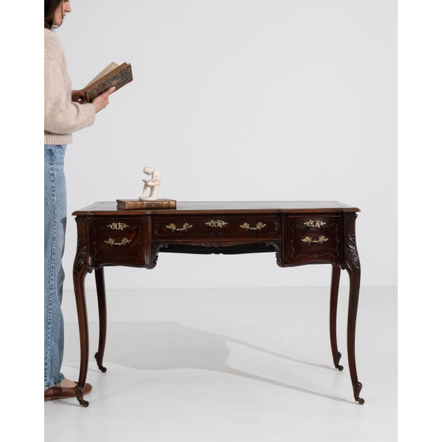 A refined Louis XV style desk featuring graceful curves, brass detailing, and functional casters for mobility. The design...