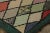 This antique 2x4 hooked rug, circa 1920–1929, features a lively harlequin diamond pattern rendered in soft pastels and...