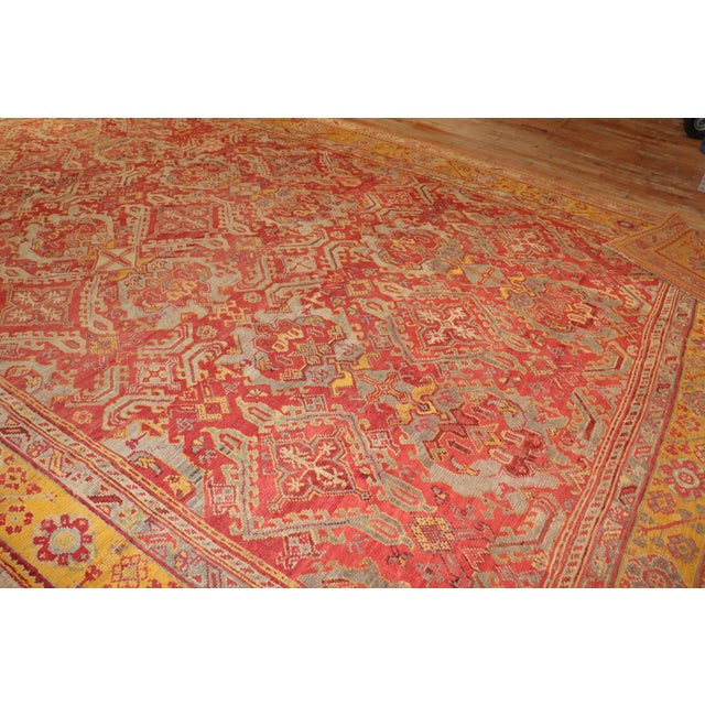 A colorful early 20th century antique Turkish Oushak rug. Predominantly Raspberry and mustard. Measures: 12'2" x 17'10".