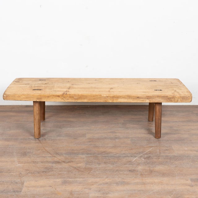 The appeal of this rustic coffee table comes from the thick wood top that originally served as a worktable, all resting...