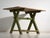 This antique trestle table in pine wood rests on two X-frame trestles tied by a central stretcher, with a plank top held...