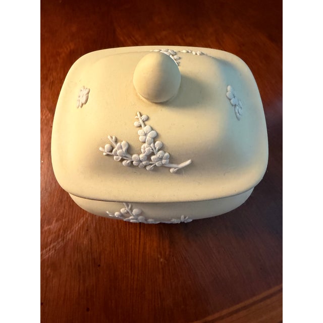The Wedgwood Yellow Primrose Rectangular Lidded Box with White Relief Prunus Blossoms is a decorative pottery trinket box...