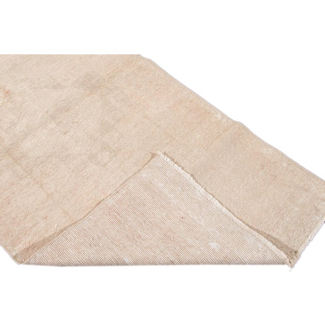 Beautiful vintage Turkish hand knotted wool rug with a beige field. This rug has tan accents in a gorgeous all-over...