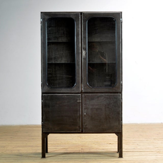 Vintage medicine cabinet from the 1970s, produced in Hungary. The cabinet is made of iron and glass, with the glass held...