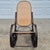 This is a vintage Thonet style bentwood rocking chair with a dark stained steam bent wood frame and natural cane back and...