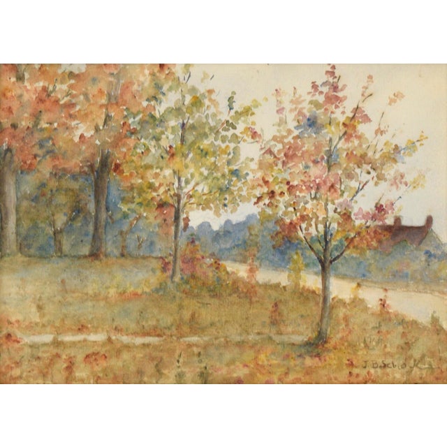 Serene landscape by J. B. Schock. Several trees line the banks of a river, bursting with fall colors. Across the river on...