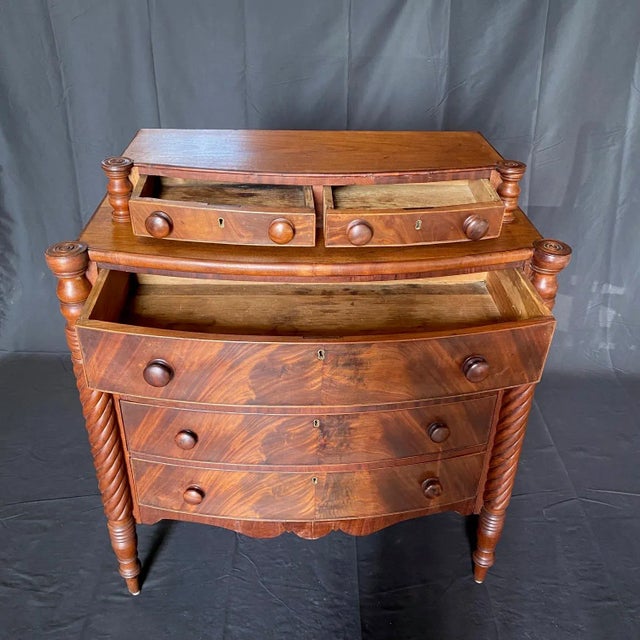 19th Century Sheraton Flame Mahogany Bow Front Chest having turret cookie cutter corners, flanked by fluted barley twist...