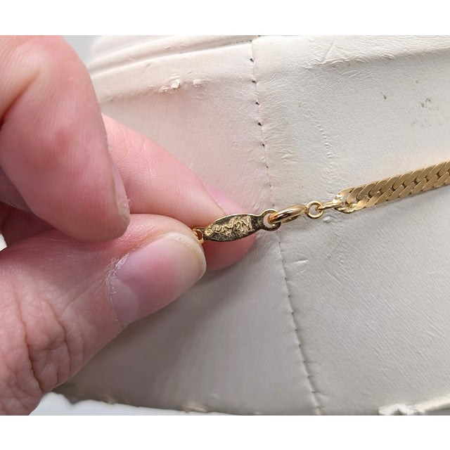 1982 goldtone line of textured white enamel leaves down the center with woven chain in the back necklace with spring ring...