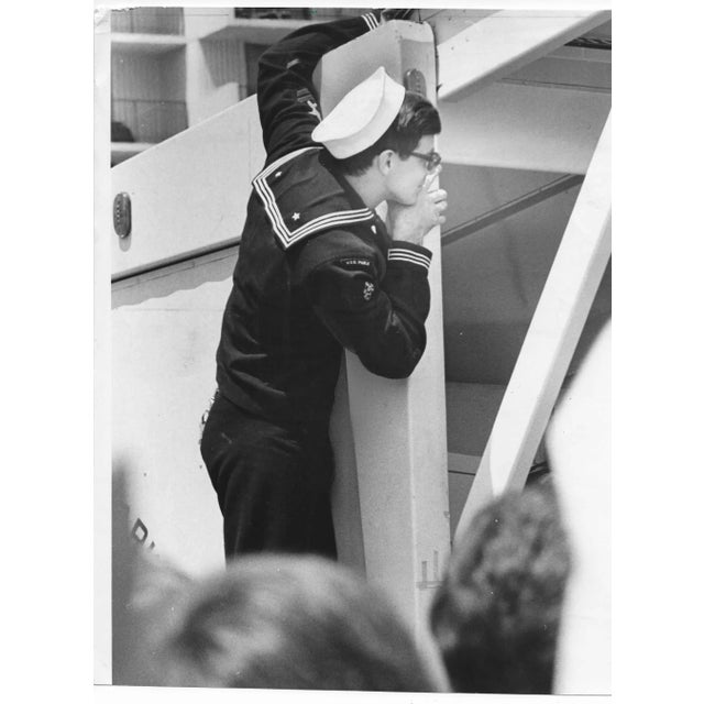 1970 photo of a US Navy Sailor trying to watch a beauty contest. Publication information on the back.