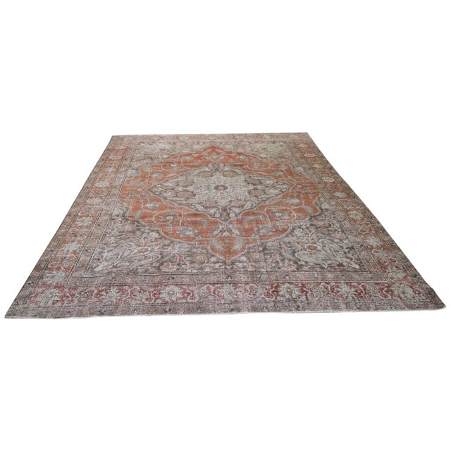 A vintage Persian rug from the 1950s featuring a rich red and rusty palette and a classic central medallion, offering...