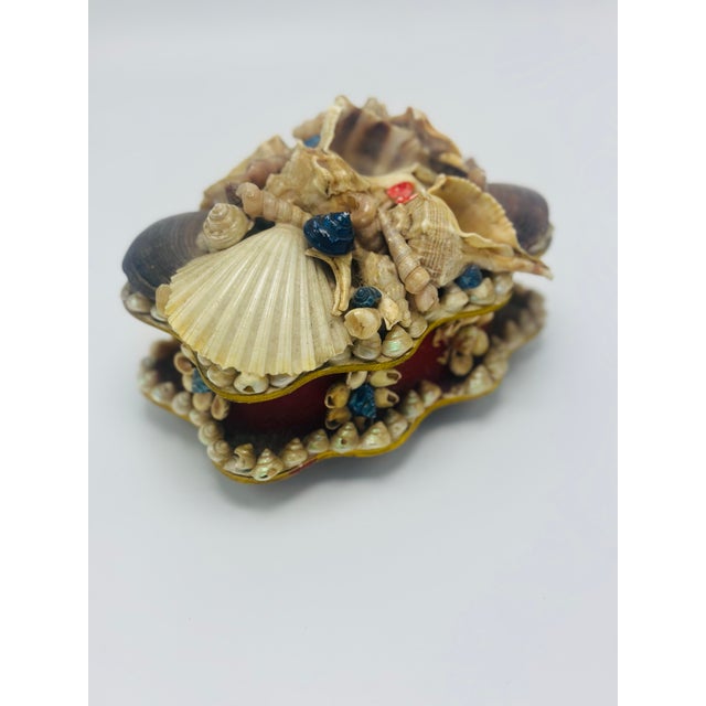This charming vintage shell-encrusted trinket box captures the whimsical spirit of mid-century coastal décor. Crafted in a...