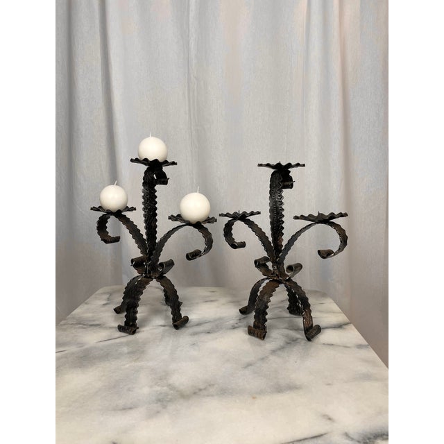 Stunning pair of handcrafted wrought iron candlesticks from the 1950s/70s. Hammered floral motifs inspired by Spanish...