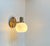 An elegantly crafted wall sconce in patinated brass featuring a frosted spherical opaline glass shade. Unknow Scandinavian...