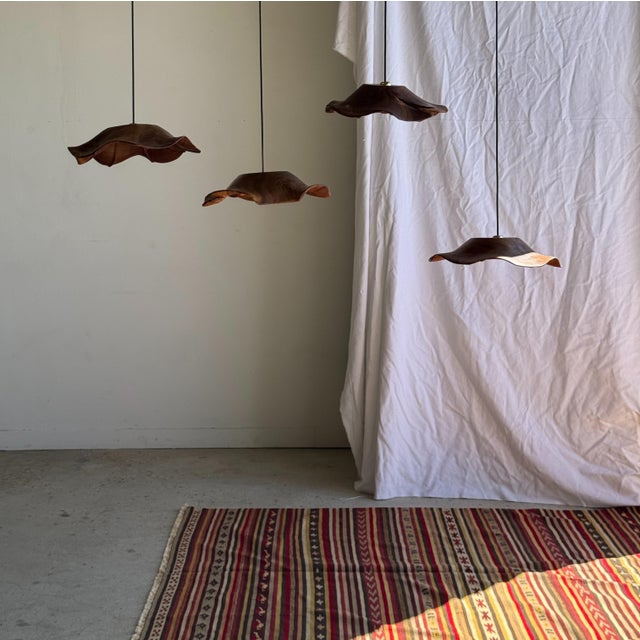 Medium-sized, flat, undulating leaf pendant light in teak with a floral grain and striations underneath. Elegant and...
