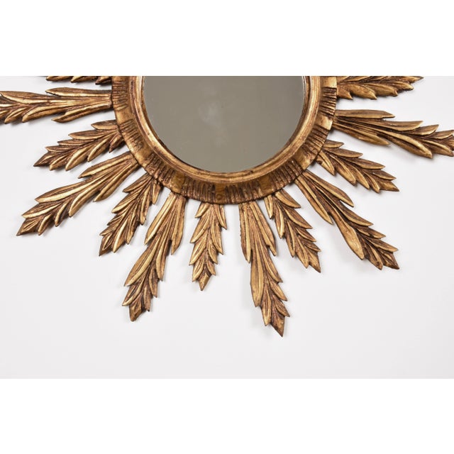 This is a wall mirror in gilded wood in a vintage sunburst design.