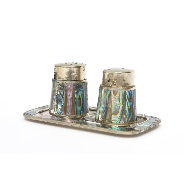 This vintage very small set of abalone and alpaca silver salt and pepper shakers have their original tray. They are...