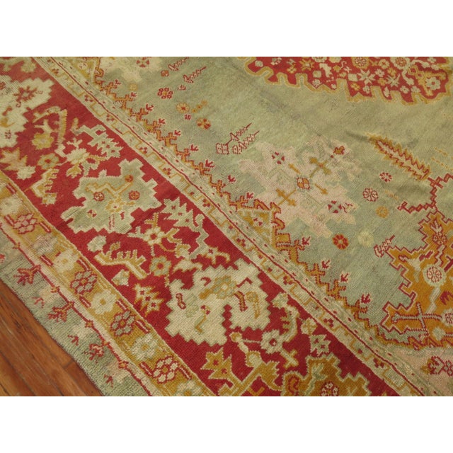 A large square early 20th-century antique Turkish Oushak rug with a light green field and red border. Full pile condition....