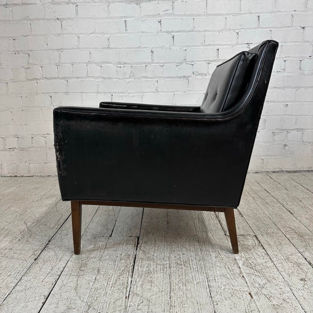 Classic mid century modern black vinyl lounge chair with walnut frame, base, and legs. This chair is well-built and heavy.