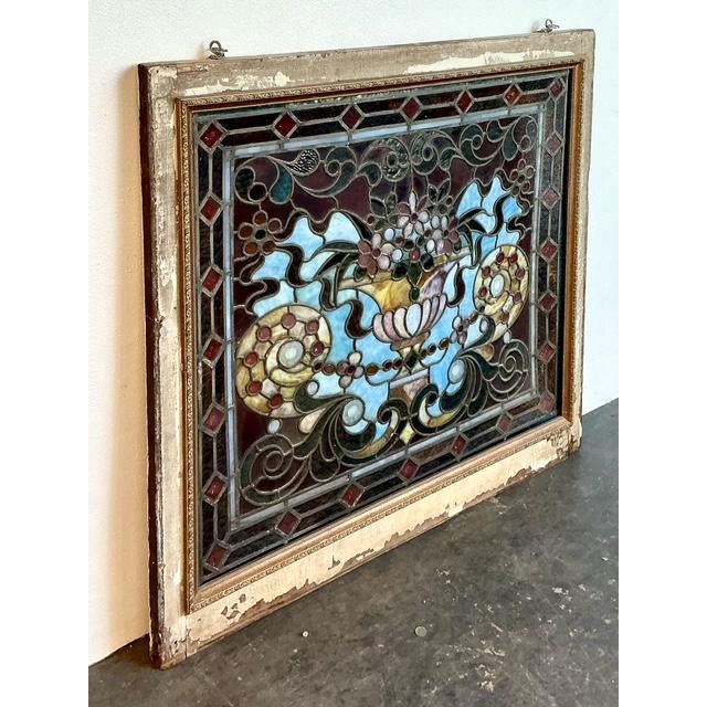 This stunning vintage stained glass window is a triumph of traditional craftsmanship, featuring a central classical urn...