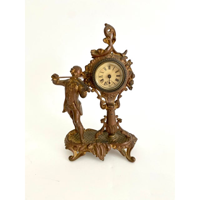 This gold cast metal clock is marked with a 1891 patent on the underside. It features a fussily dressed violinist beside...