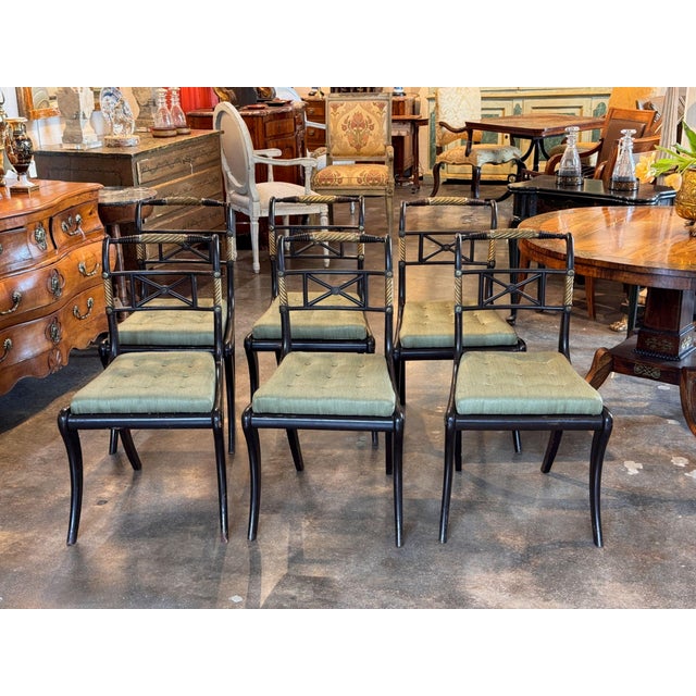 A set of six 19th century black and gilt side chairs, each with a gently curved crest rail carved as a gilded rope twist...