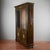An elegant two-piece display cabinet, a prized antique piece evoking the opulence of the neoclassical or eclectic style,...