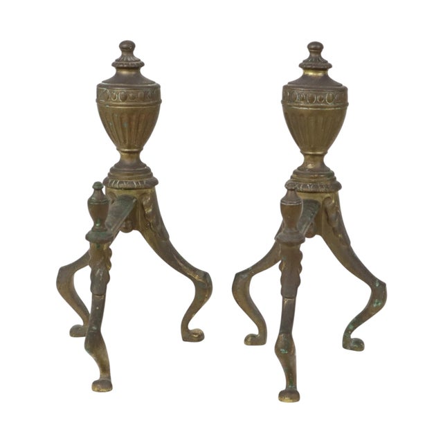 A pair of antique British fire dogs featuring a beautiful patina from age and use; high-quality brass construction, marked...